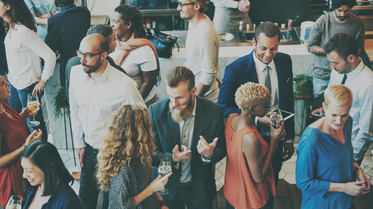 A crowd of young professionals happily mingling at an event