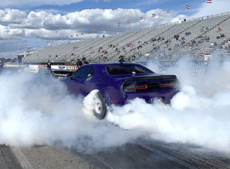 Purple Dodge Challenger smoking its tires on a drag strip