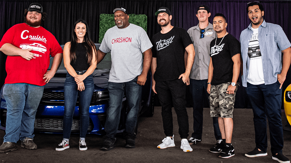 Group of racecar drivers standing in front of a car