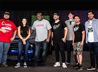 Group of racecar drivers standing in front of a car