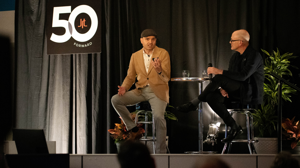 Mark Bellissimo of the JRT agency and Nikola Danaylov of Singularity in an event photo of lighted stage and JRT 50th logo