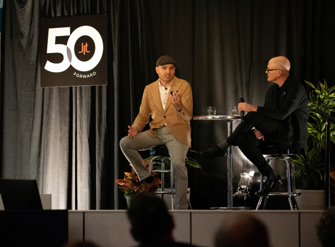 Mark Bellissimo of the JRT agency and Nikola Danaylov of Singularity in an event photo of lighted stage and JRT 50th logo