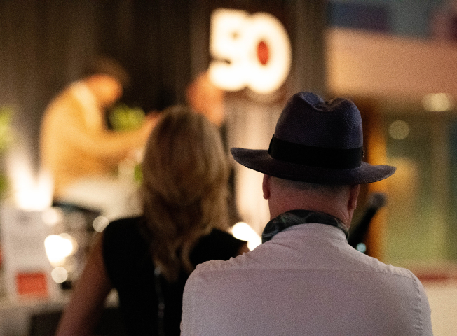 The audience listens intently at the JRT agency in an event photo of lighted stage and 50th logo