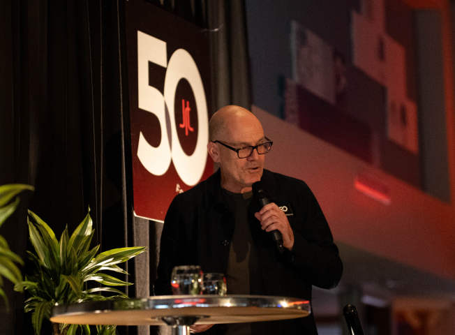 Mark Bellissimo of the JRT agency in an event photo of lighted stage and 50th logo