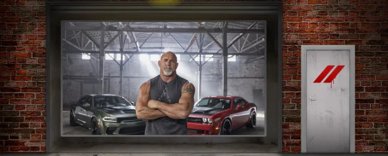 A garage with two cars and a person standing with his arms crossed