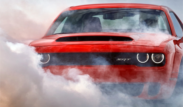 A red Dodge SRT vehicle sits among smoke